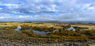 Panoramic view of Silver Creek Idaho, oxbow channels winding through sagebrush flats under dramatic cloud-broken sky — fine art landscape print by Jess Lee