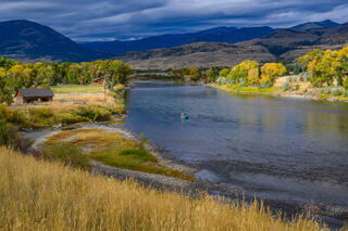 Drift boat on Yellowstone River, Paradise Valley Montana, autumn cottonwoods gold, historic homestead cabin, Absaroka Range beyond — fine art print by Jess Lee