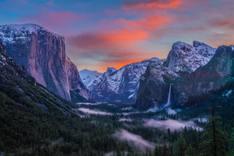 Yosemite National Park from the iconic Tunnel View. The early morning light gently kisses the snow-capped peaks, casting a warm glow that contrasts beautifully 