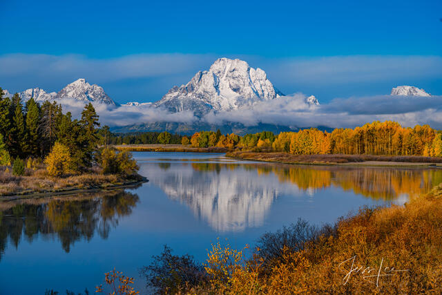 Teton Fall reflection with snowy mountain and fall colored trees along the snake river oxbow bend.