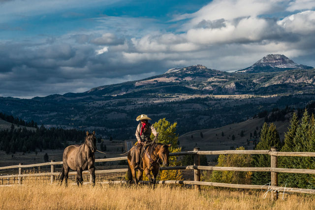 Cowgirl leading horse in evening light