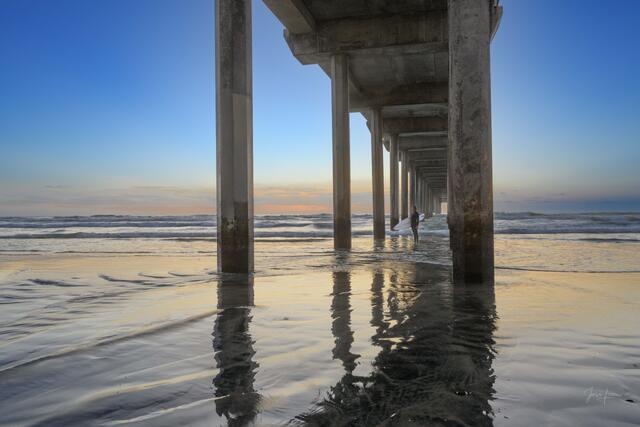 Lone Surfer on the California Coast standing under the Scripps Pier