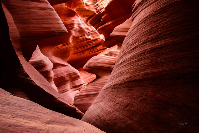 Vertical view of glowing orange and red sandstone curves forming a narrow passage inside Antelope Canyon near Page, Arizona.