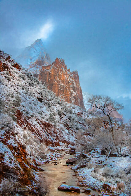 Vertical landscape photo print of a snowy mountain path leading toward a red sandstone peak under a blue sky.