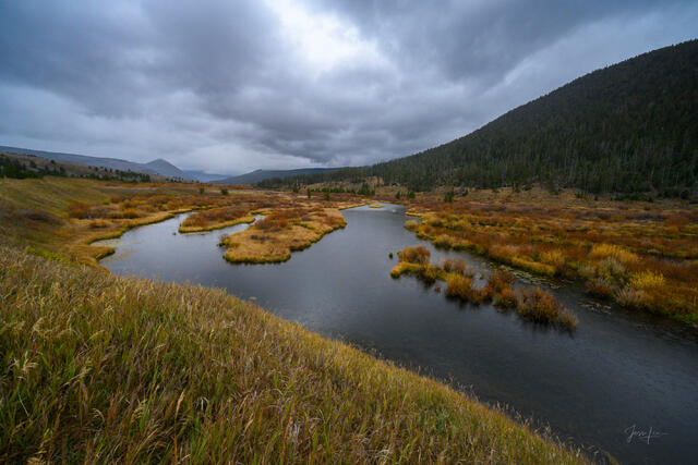 Braided Gallatin River winding through golden autumn meadows under dramatic storm clouds, Montana — fine art landscape print by Jess Lee