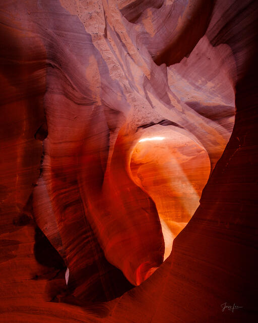 Glowing light beam illuminating the swirling red sandstone walls of Antelope Canyon, Arizona