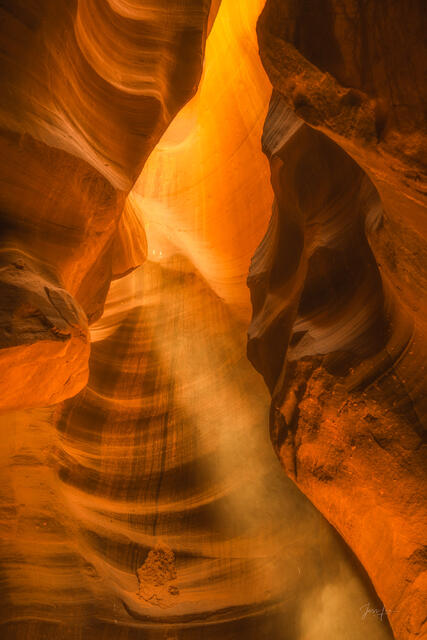 A vertical beam of sunlight illuminating dust in Antelope Canyon's glowing sandstone slot