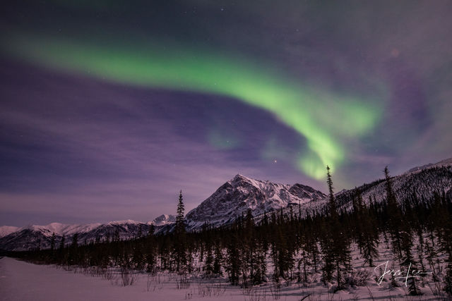 Aurora Borealis over a snow-covered Alaskan mountain range. 