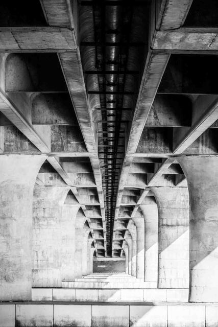 Vertical photo of a underneath of a concrete bridge leading to infinite