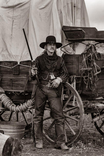 Old Time Cowboy Black and White Sepia Print. Plainsman with Henry Rifle at his covered wagon