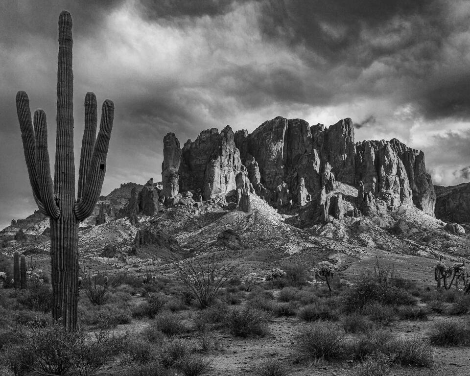 Fine art black and white photograph of the Superstition Mountains with dramatic storm clouds and saguaro cacti. Arizona photography print.